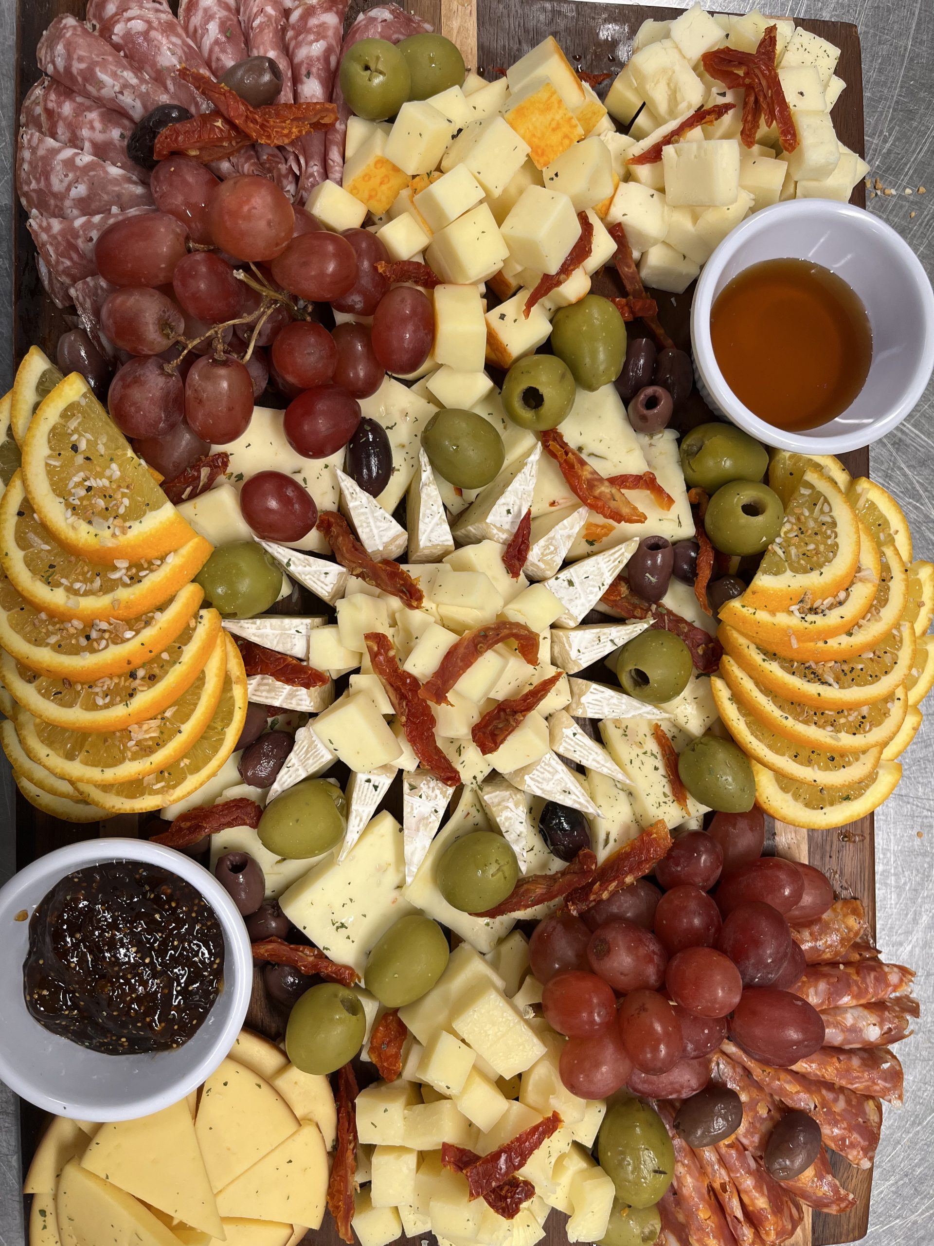 A platter of cheese, olives, and grapes.