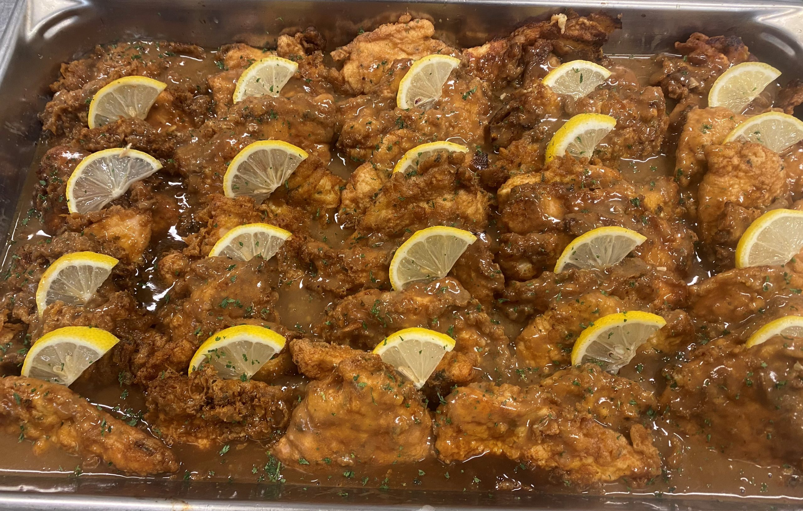 Fried chicken with lemon wedges on a tray.