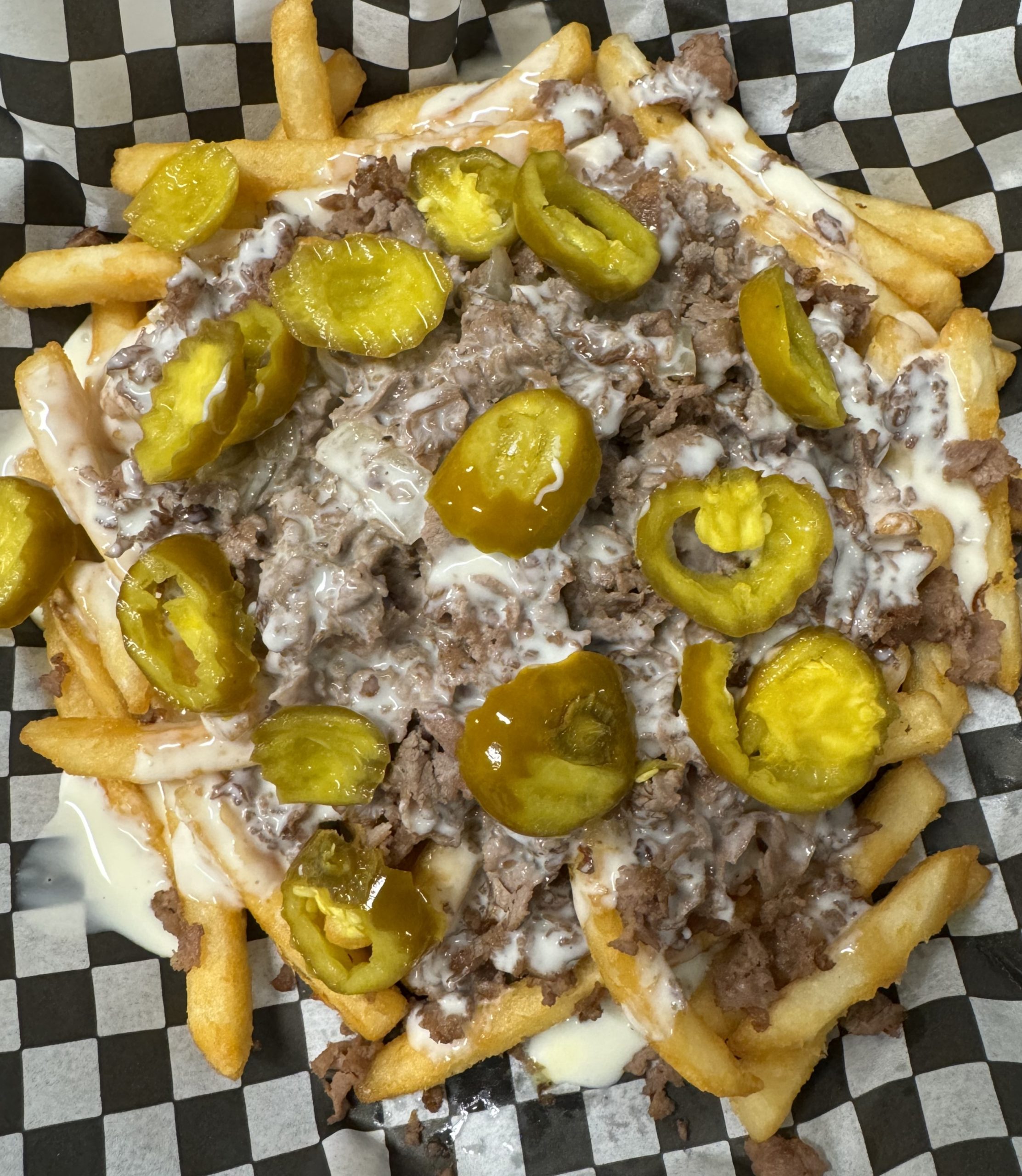 A plate of french fries with meat and pickles.