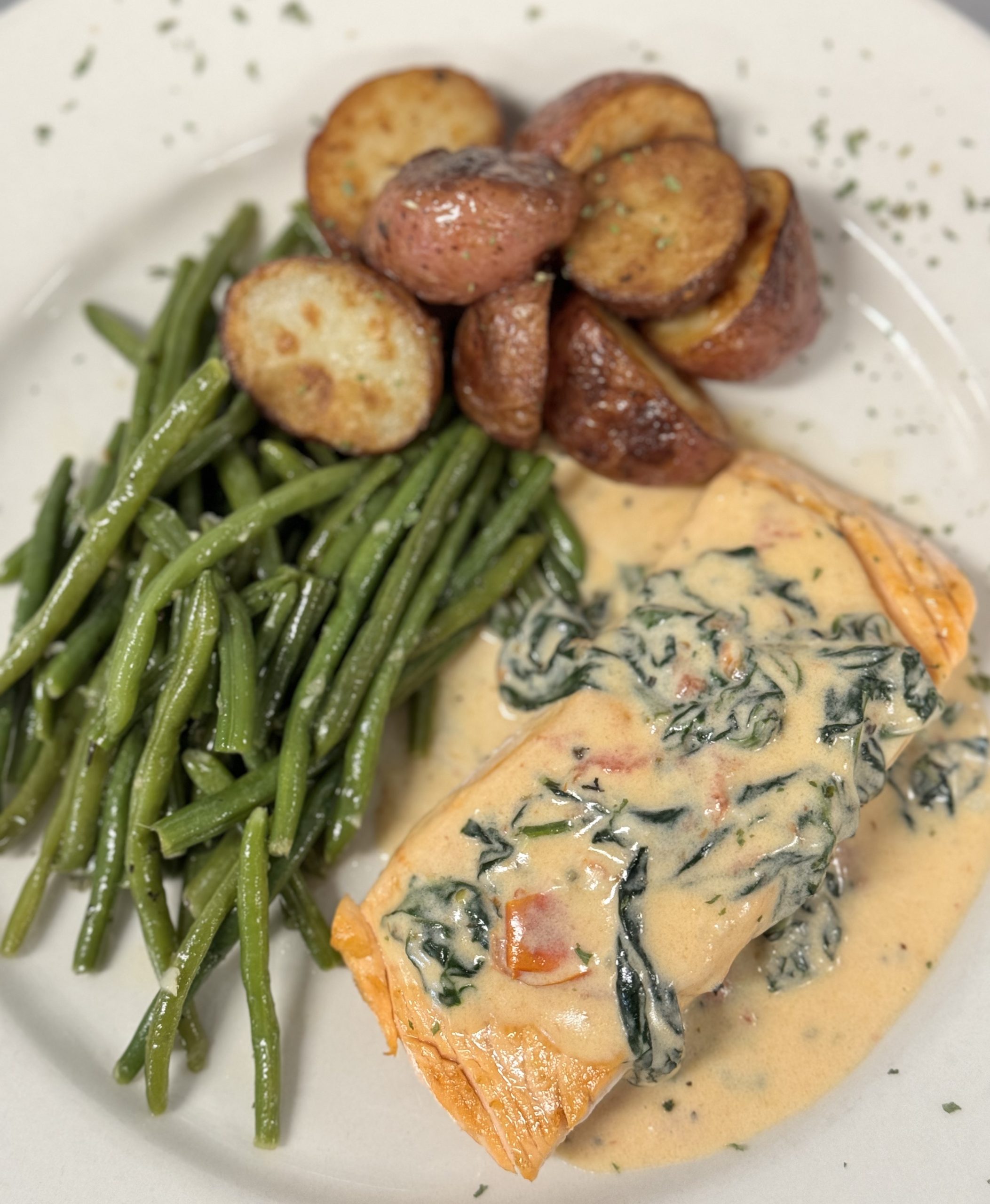 A plate with salmon, green beans and potatoes.